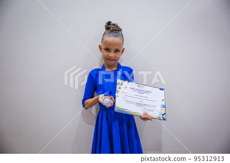 Beautiful happy smiling gymnast and dance girl in sportswear dress showing her medals. Beautiful happy smiling gymnast and dance girl in sportswear dress showing her medals. 95312913