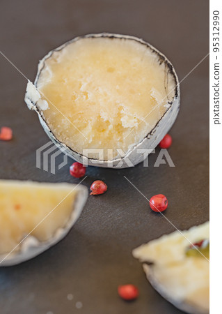 Belper knole with garlic and pink pepper in wood ash on black slate. Close-up view. Selective focus. 95312990