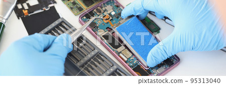 Hands with tweezers repairing a battery from a smartphone Hands with tweezers repairing a battery from a smartphone 95313040