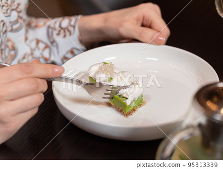 Cropped view of woman cutting healthy dessert with a fork Cropped view of woman cutting healthy dessert with a fork 95313339