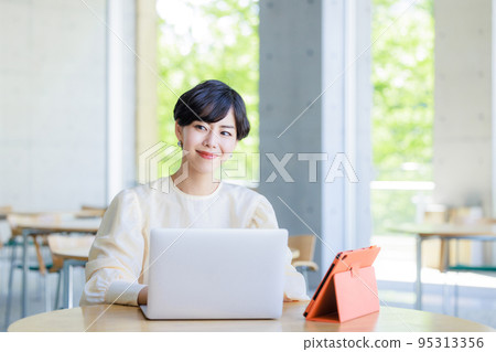 A woman working on a computer in a cafe 95313356