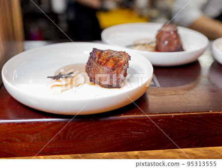 Beef fillet on a white plate in sauce on the countertop 95313555