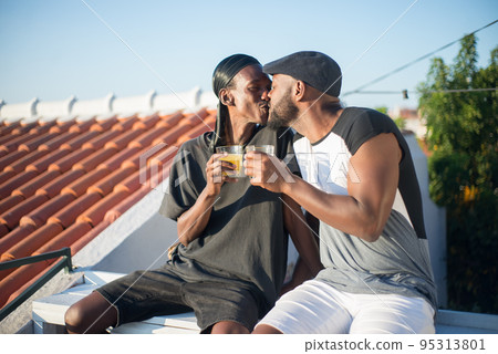 Portrait of happy African gay couple enjoying kisses on bench 95313801
