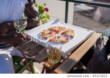 Close-up of two sitting men and slices of pizza on table 95313825