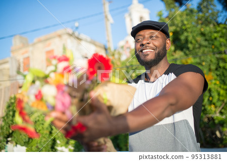 Close-up of happy African American man presenting flowers 95313881