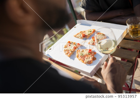 Close-up of two men having quick bite with slices of pizza Close-up of two men having quick bite with slices of pizza 95313957
