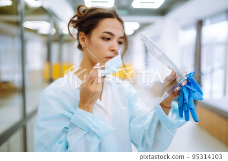Young Nurse take off protection mask and visor after a work day. Disease control expert at office. Young Nurse take off protection mask and visor after a work day. Disease control expert at office. 95314103