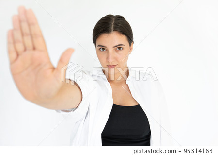 Portrait of serious young woman making stop gesture 95314163
