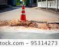 traffic cone on damaged road surface 95314273