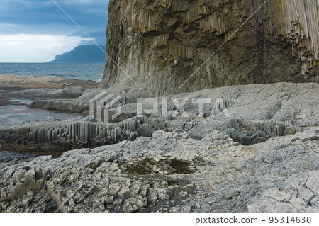 rocky seashore formed by columnar basalt against the backdrop of a stormy sea, coastal landscape of the Kuril Islands rocky seashore formed by columnar basalt against the backdrop of a stormy sea, coastal landscape of the Kuril Islands 95314630