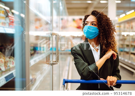 Young woman wearing face mask buying in supermarket. Shopping during the pandemic. Covid-2019. Young woman wearing face mask buying in supermarket. Shopping during the pandemic. Covid-2019. 95314678