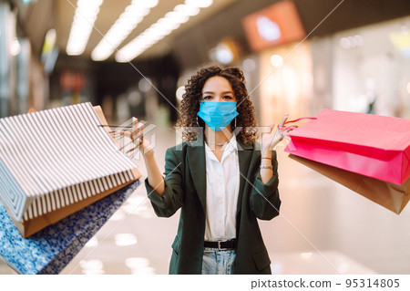 Young woman wearing protection face mask against coronavirus after shopping in the mall. Covid-2019. 95314805