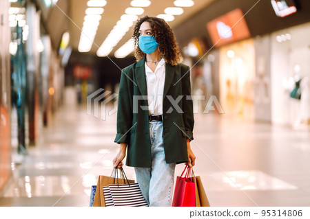 Young woman wearing protection face mask against coronavirus after shopping in the mall. Covid-2019. Young woman wearing protection face mask against coronavirus after shopping in the mall. Covid-2019. 95314806