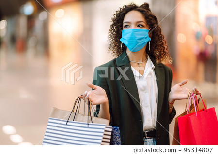 Young woman wearing protection face mask against coronavirus after shopping in the mall. Covid-2019. Young woman wearing protection face mask against coronavirus after shopping in the mall. Covid-2019. 95314807