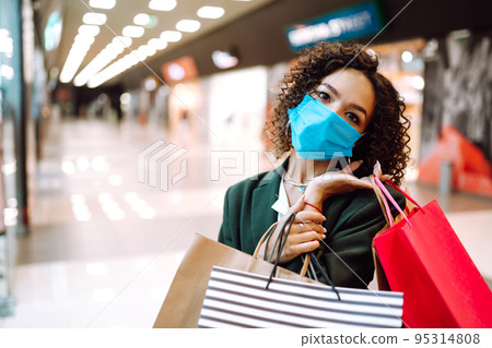 Young woman wearing protection face mask against coronavirus after shopping in the mall. Covid-2019. Young woman wearing protection face mask against coronavirus after shopping in the mall. Covid-2019. 95314808