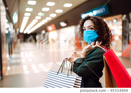 Young woman wearing protection face mask against coronavirus after shopping in the mall. Covid-2019. Young woman wearing protection face mask against coronavirus after shopping in the mall. Covid-2019. 95314809