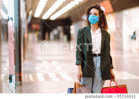 Young woman wearing protection face mask against coronavirus after shopping in the mall. Covid-2019. Young woman wearing protection face mask against coronavirus after shopping in the mall. Covid-2019. 95314811