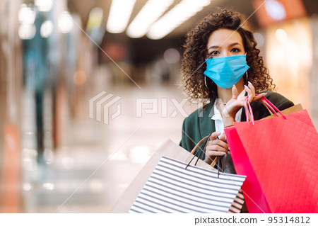 Young woman wearing protection face mask against coronavirus after shopping in the mall. Covid-2019. Young woman wearing protection face mask against coronavirus after shopping in the mall. Covid-2019. 95314812