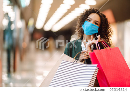 Young woman wearing protection face mask against coronavirus after shopping in the mall. Covid-2019. Young woman wearing protection face mask against coronavirus after shopping in the mall. Covid-2019. 95314814