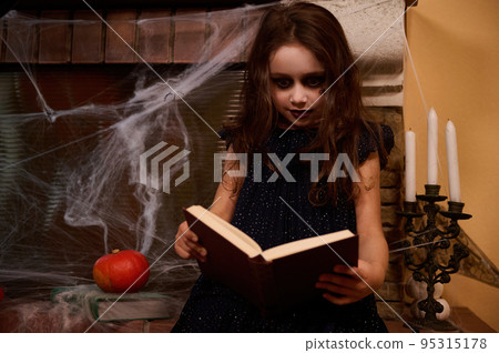 Gothic child girl, mystical witch, sorceress with a book of spells , sitting by a spider web covered fireplace and mysterious candles on the candlestick, whispering sorcery on the Halloween night Gothic child girl, mystical witch, sorceress with a book of spells , sitting by a spider web covered fireplace and mysterious candles on the candlestick, whispering sorcery on the Halloween night 95315178