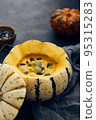 Pumpkin cream soup served in a squash with seeds 95315283
