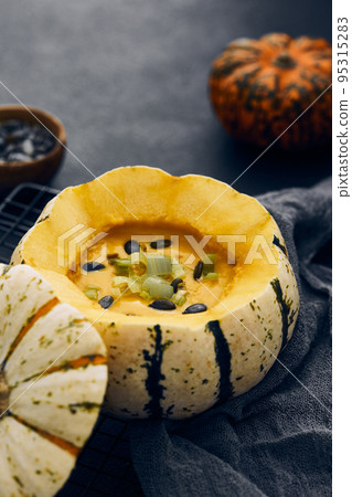 Pumpkin cream soup served in a squash with seeds 95315283
