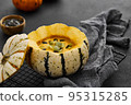 Pumpkin cream soup served in a squash with seeds 95315285