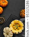 Pumpkin cream soup served in a squash with seeds 95315286