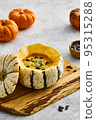 Pumpkin cream soup served in a squash with seeds 95315288