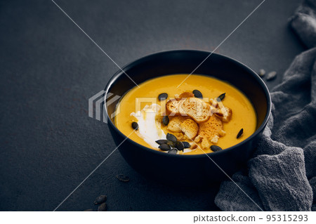 Pumpkin cream soup with croutons on dark background 95315293