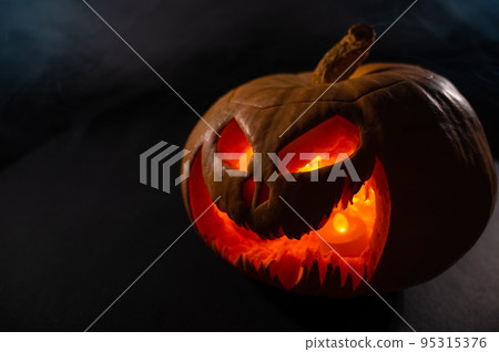 A creepy pumpkin with a carved grimace glows. Jack on a lantern in the dark. A creepy pumpkin with a carved grimace glows. Jack on a lantern in the dark. 95315376