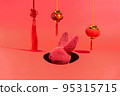 A red rabbit in a hole surrounded by New Year's decorations on a red background 95315715