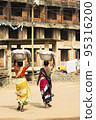 Two Indian women carrying a basket of fish on their head  95316200