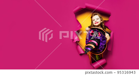 a little girl in a witch costume peeks out of a hole in a paper background a little girl in a witch costume peeks out of a hole in a paper background 95316943