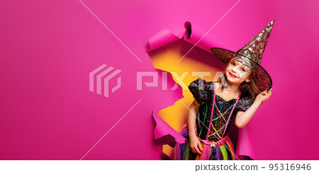 a little girl in a witch costume peeks out of a hole in a paper background a little girl in a witch costume peeks out of a hole in a paper background 95316946