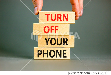 Turn off your phone symbol. Concept words Turn off your phone on wooden blocks. Beautiful grey table grey background. Businessman hand. Business psychological turn off your phone concept. Copy space Turn off your phone symbol. Concept words Turn off your phone on wooden blocks. Beautiful grey table grey background. Businessman hand. Business psychological turn off your phone concept. Copy space 95317115