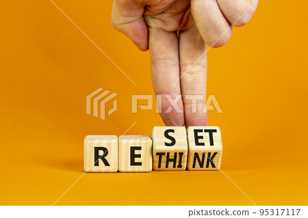 Rethink and reset symbol. Businessman turns wooden cubes and changes the concept word Rethink to Reset. Beautiful orange table orange background. Business rethink and reset concept. Copy space. Rethink and reset symbol. Businessman turns wooden cubes and changes the concept word Rethink to Reset. Beautiful orange table orange background. Business rethink and reset concept. Copy space. 95317117