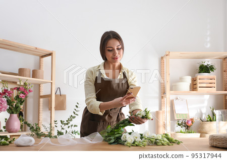Florist taking picture of beautiful flowers in workshop 95317944
