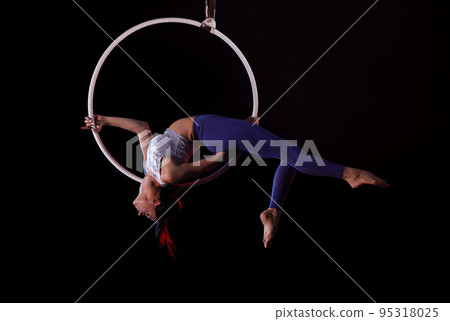 Young woman performing acrobatic element on aerial ring indoors Young woman performing acrobatic element on aerial ring indoors 95318025