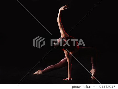 Young woman performing acrobatic element on stage indoors 95318037