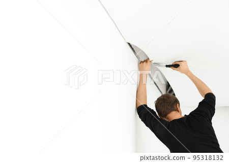 Repairman installing white stretch ceiling in room Repairman installing white stretch ceiling in room 95318132