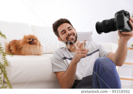 Professional animal photographer taking selfie with beautiful Pomeranian spitz dog indoors Professional animal photographer taking selfie with beautiful Pomeranian spitz dog indoors 95318502