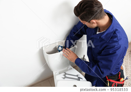 Professional plumber working with toilet bowl in bathroom 95318533
