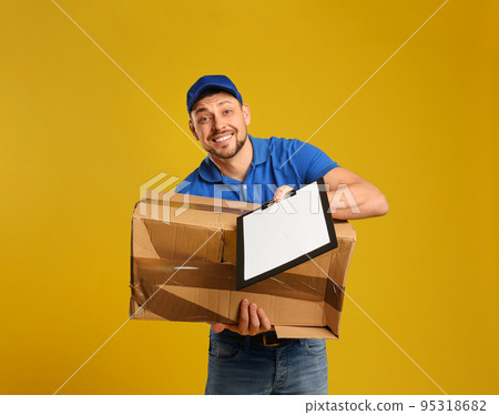 Emotional courier with damaged cardboard box and clipboard on yellow background. 95318682