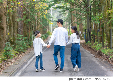 A family of three with a parent-child outfit walking hand in hand A family of three with a parent-child outfit walking hand in hand 95318749