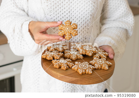 Christmas shortbread snowflakes. Women's hands hold traditional New Year's gingerbread 95319080