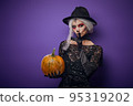 Witch with grey hair whispering in Halloween costume 95319202