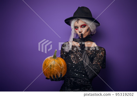 Witch with grey hair whispering in Halloween costume Witch with grey hair whispering in Halloween costume 95319202