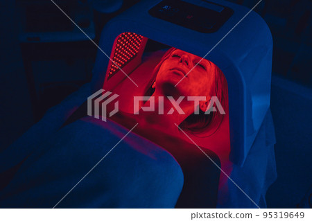 LED red light is treating the facial skin of a young woman. LED red light is treating the facial skin of a young woman. 95319649