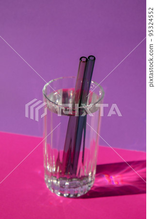 Reusable glass Straws in Glass with water on purple violet background Eco-Friendly Drinking Straw Set with cleaning brush. Zero waste, plastic free concept 95324552